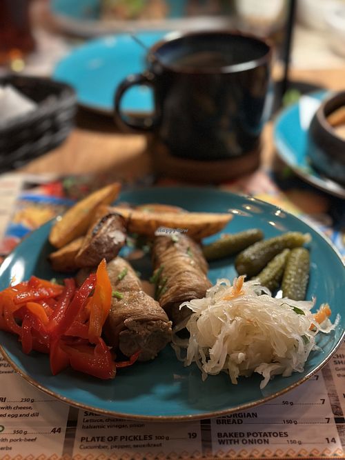 A mix of different vegan dishes, backed potato with onion, plate of pickles and aubergine rolls  at Chinkalnia Restauracja Gruzińska in Gdansk
