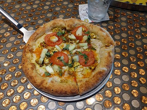 vegan pizza including thai curry, cucumbers, tomatoes, and tofu at Mellow Mushroom in Lincoln