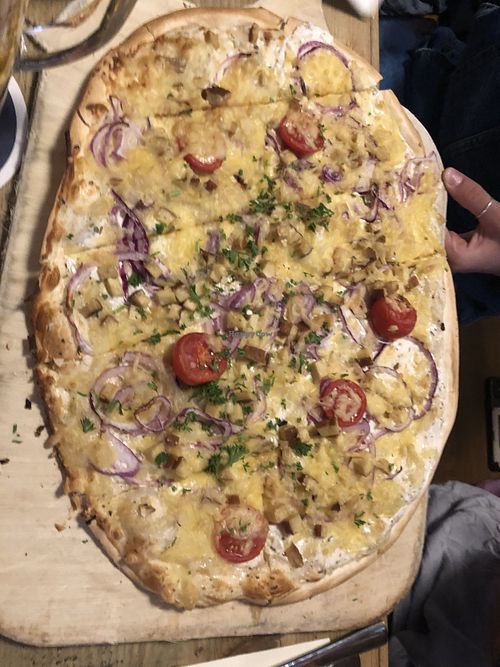 Flammkuchen (typical dish from the region) with plant based cheese, onions, tomatoes and tofu  at Schwarzer Kater in Freiburg