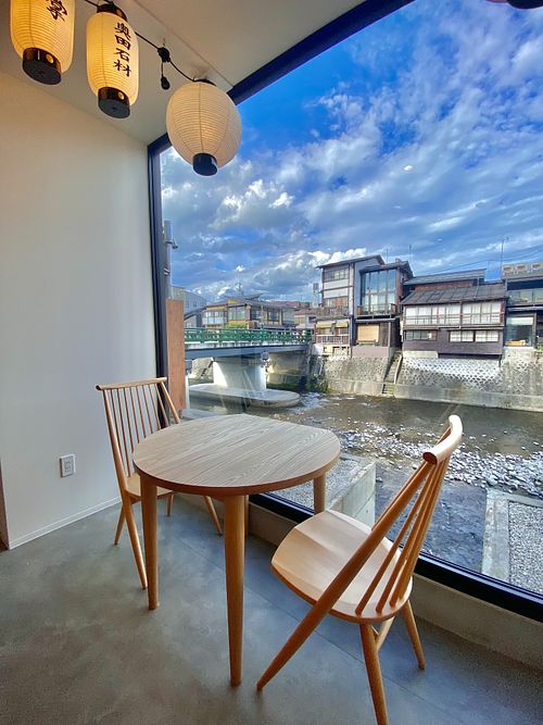 The bright, modern interior offers a cozy atmosphere and a view overlooking the Miyagawa river. Seating consists of seven counter seats and six two-top tables, all locally crafted from Hida-Takayama wood.  at Ramen Kamon in Takayama
