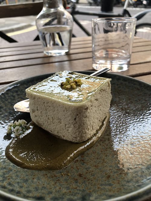 The cheesecake sitting in a pistachio sauce  at Kin Restaurant in London