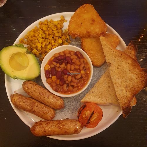 PLANT-BASED BREAKFAST: Avocado, three THIS™ Isn’t Pork sausages, two hash 
browns, half a grilled tomato, roasted sweetcorn and toast, served with lightly spiced beans. at Slug & Lettuce - Albert Square in Manchester