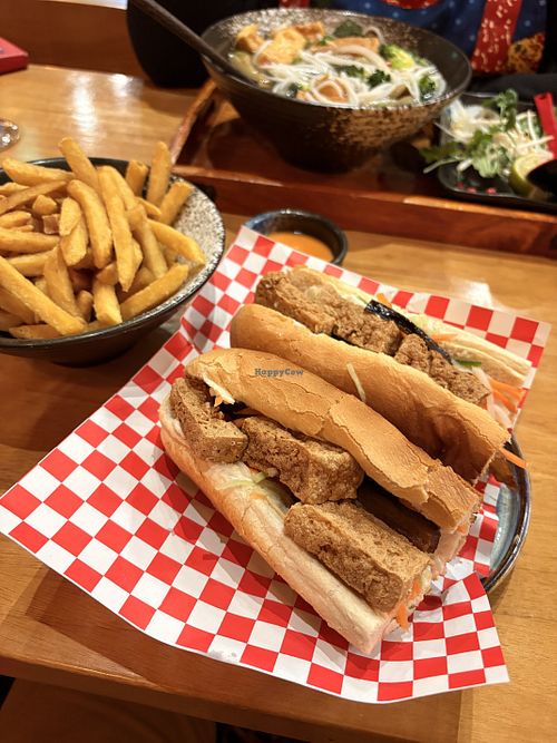 Vegan Banh Mi sandwich cut in half, revealing layers of crispy tofu, eggplant, pickled carrots and daikon, cucumber, coriander, and vegan mayo inside a crusty baguette.  at Madame Pho - Exchequer St  in Dublin