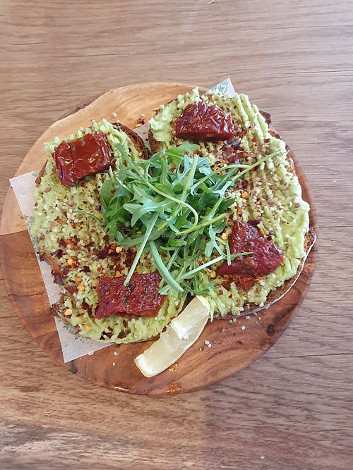 Loaded avo toast: Fresh smashed avocado, black pepper, hemp seeds, flax seeds, pumpkin seeds, sundried tomato, chilli flakes and rocket on toasted sourdough at The Plant Boost in Wilmslow