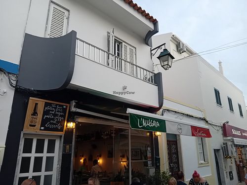 The front of the building advertising gluten free and vegan pasta, pizza and desserts at Trattoria L'Allegria in Alvor