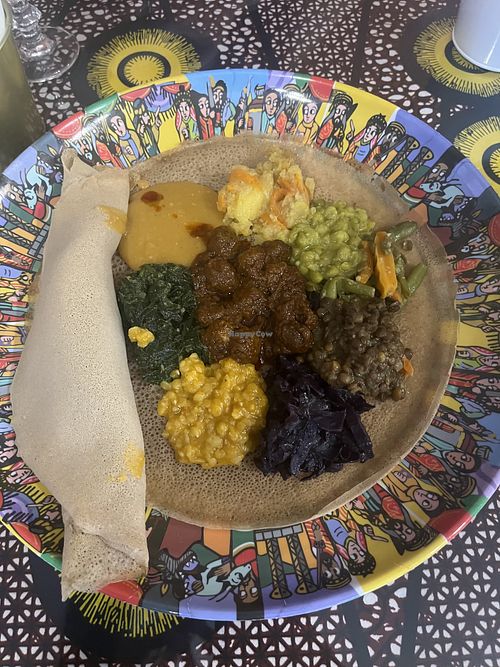 Vegetarian mix - potatoes, green peas, green beans with carrot, green lentils, purple cabbage, yellow peas, spinach, pea puree from top clockwise. Soy chunks in spicy sauce middle  at Habesha 2 Restaurant in Emilia-romagna