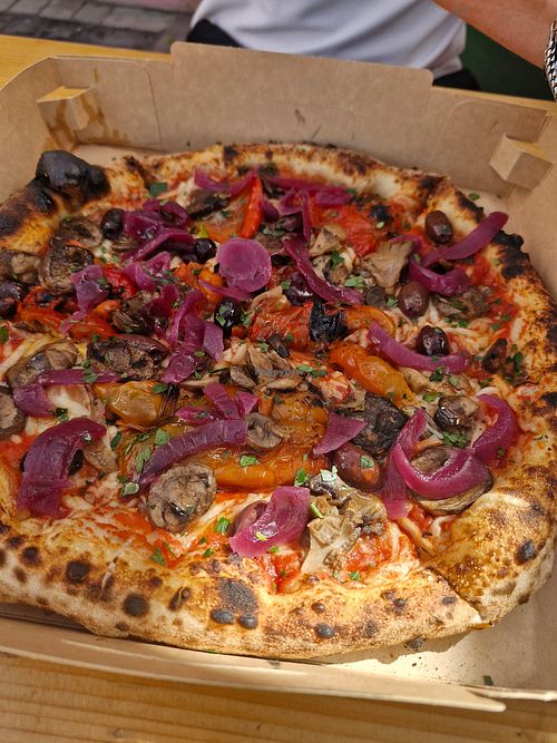 Neapolitan pizza with mushrooms, bell peppers, sweet onion, fresh olives and tomatoes and vegan cheese. Drizzled with garlic oil and sprinkled with parsley at Semo. Italian Street Kitchen  in Copenhagen