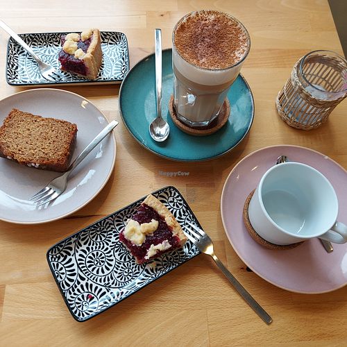 Drei Stück vegane Kuchen, ein Chai Latte mit Hafermilch und eine Tasse für Filterkaffee. at Café Frau Elster in Nuremberg