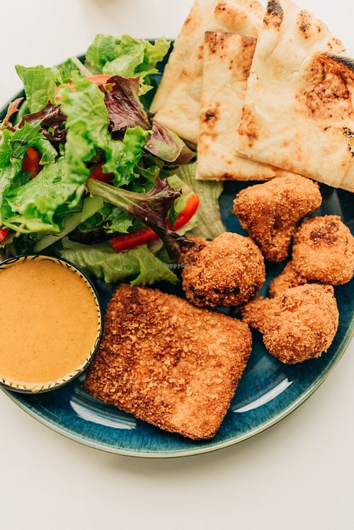 Naan bread, tandoori tofu patty, crispy cauliflower florets, fresh salad and creamy coconut curry sauce. at Saatvik Cuisine Végé in Magog