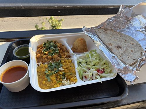 Platter with half chickpeas and half lentils, samosa, rice, and salad; staff is glad to substitute vegan roti for nonvegan naan.  at Yossi Kitchen in Athens