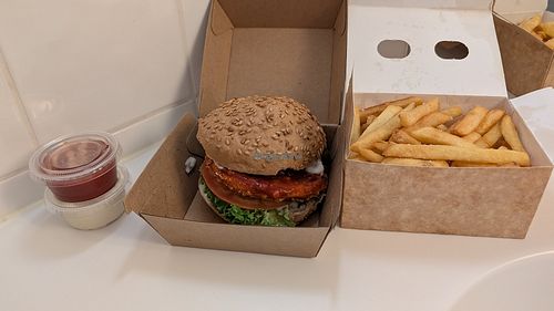 Crispy vegan burger and fries (forgot to check if vegan) takeout in sterile hotel bathroom lighting at Burger Garage Vesterbro in Copenhagen