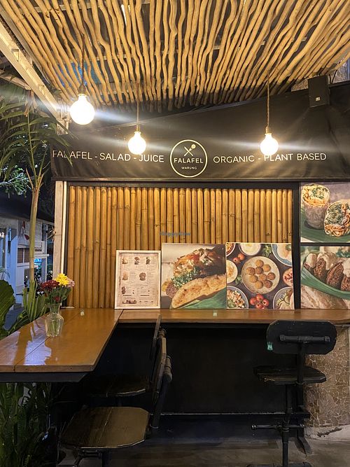 This is the type of seating that they have and you can see people passing by  at Falafel Warung in 