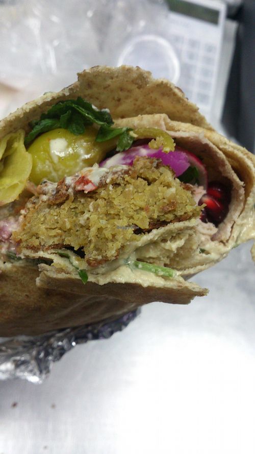 Falafel pita with vegetables, tahini sauce, hummus, pomegranate and vegan cheese. at Falafel Bejrut - Moliera in Warsaw