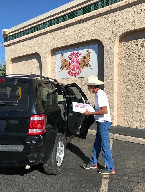 Lewis G. bringing a box of vegan donuts to a Ford Escape in the parking lot of Rebel Donuts. at Rebel Donuts - Wyoming Blvd in Albuquerque