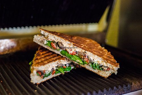 Fiery Fun-Gi-Focaccia, spicy goat cheese, black bean hummus, candied jalapeños, roasted red peppers, portobellos, greens. at Cultivate Cafe in Destin