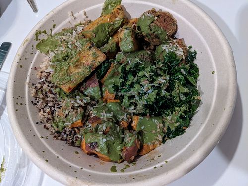 Brown rice quinoa base, kale, sweet potatoes, lentil meatballs, toasted coconut, corn fritters with walnut pesto herb green sauce at Della Bowls in Miami