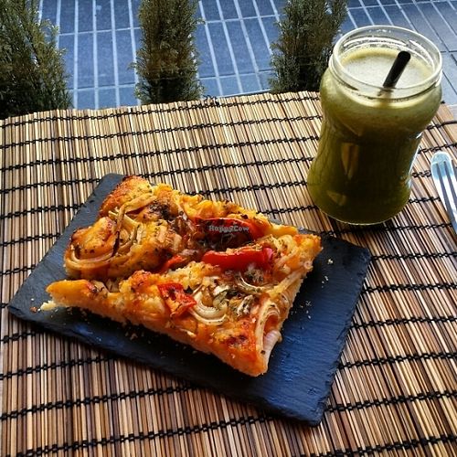 A piece of pizza with vegan mozzarella and 'chlorofil' juice! at Bioloco in Gran Canaria