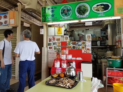 Boss introducing his dishes to passing customers, high quality mushrooms being prepared in the foreground. at Zi Fu Lin Vegetarian in East Singapore