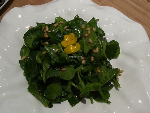 pea shoots with an edible flower on top at Philanthropian Veganism Restaurant in Beijing